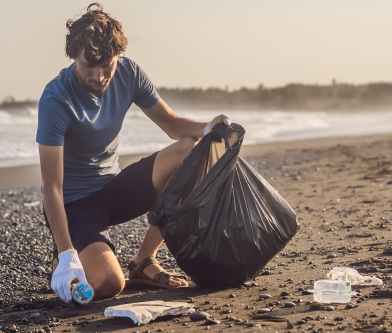 man cleaning up garbage on the beach